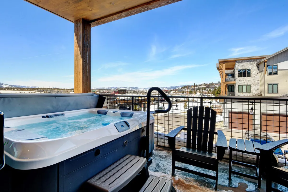 A different angle on outdoor leisure, this image features a hot tub surrounded by Adirondack chairs on a deck overlooking the natural landscape. The setting is tranquil, perfect for stargazing or catching the last light of the day with friends.