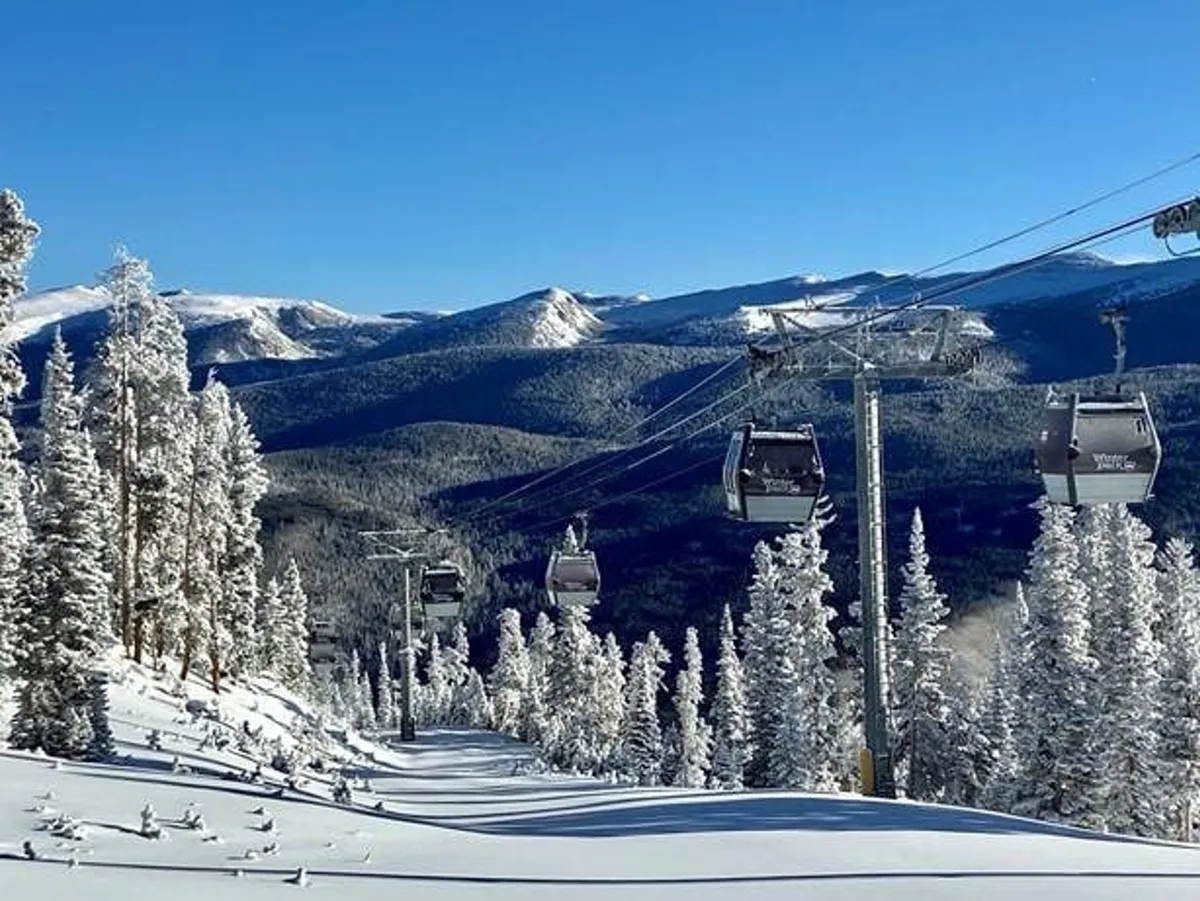 A dynamic view of Winter Park Resort with gondola lifts ascending snowy mountain slopes, distant mountain ranges, and skiers in action. The scene is invigorated by the glow of sunrise and hints at the après-ski culture with social gatherings visible at the base.